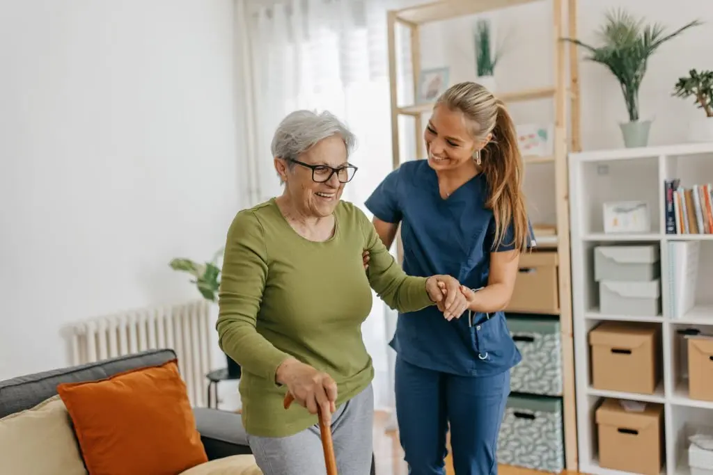 Female caregiver helping and supporting senior patient